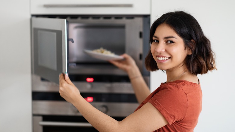 Woman placing dish in microwave