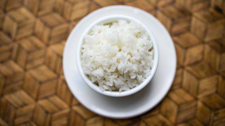 Overhead white bowl of rice on white plate