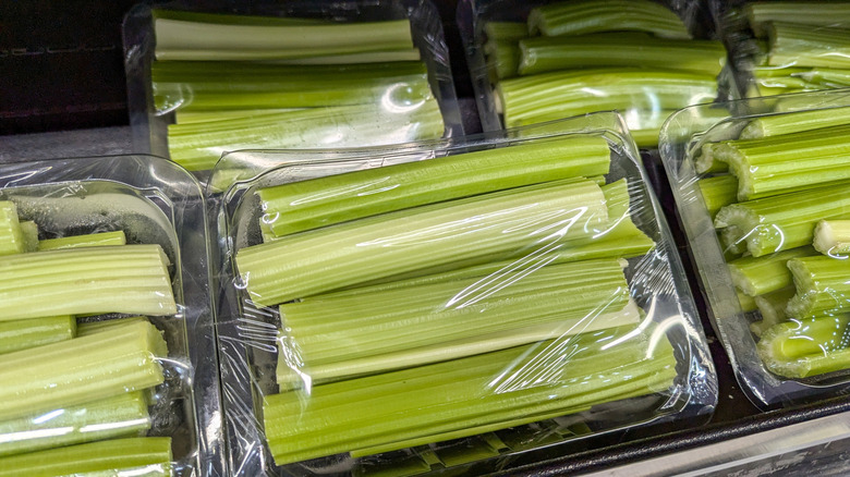 Plastic-wrapped celery in a store aisle
