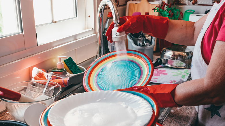 Person washing party dishes in a sink that's full