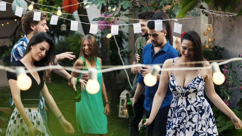 Friends partyting in the yard beneath string lights and lanterns