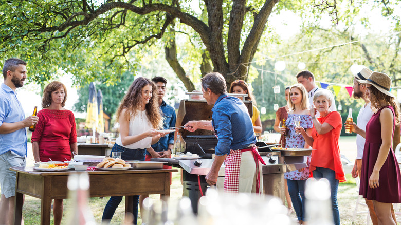 People gathered outside around a grill and having a party