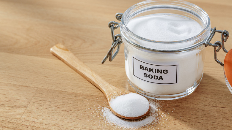 Baking soda jar with spoon on table