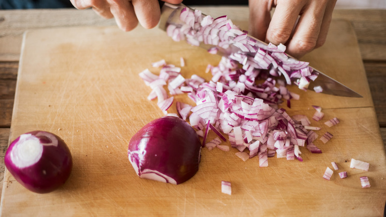 Red onions are chopped on a cutting board