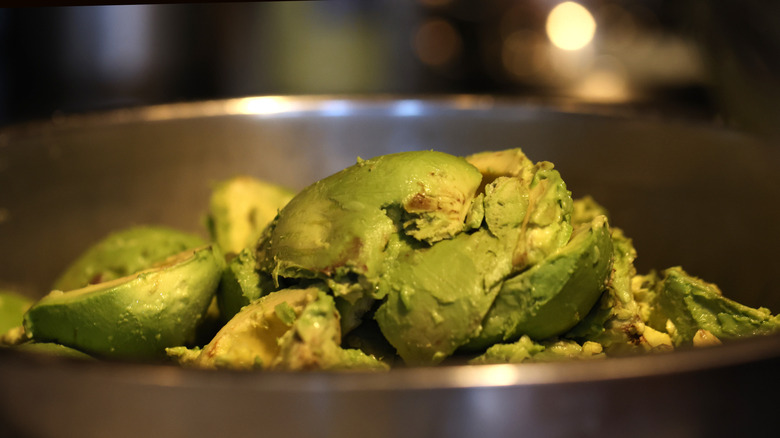 Peeled avocados sit in a bowl