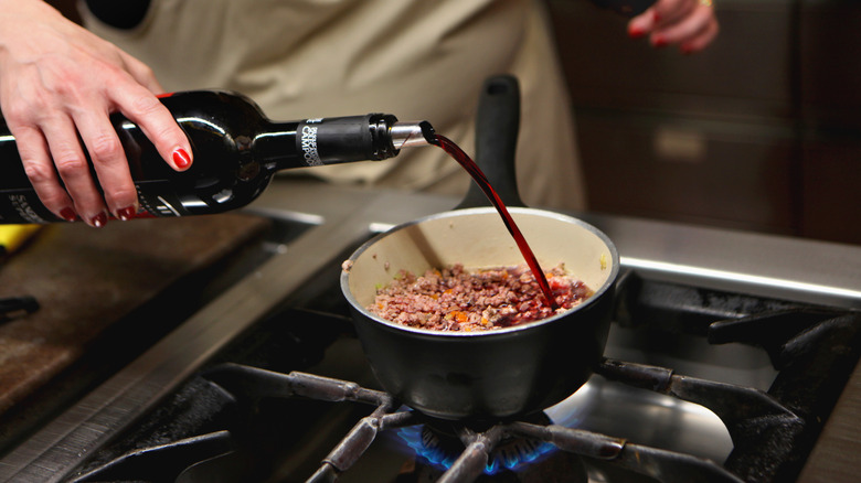 Chef adding wine to a sauce pan