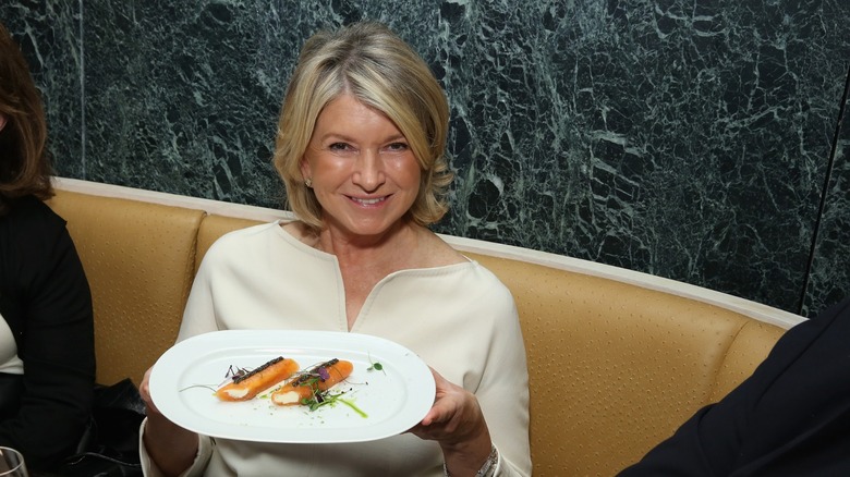 Martha Stewart holding a white plate of orange food