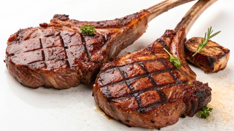Grill-marked lamb chops on a white background with parsley garnishes