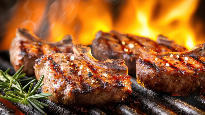 Lamb chops being marked on a grill with flames in the background