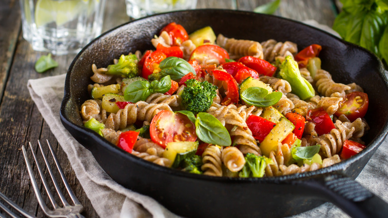 A cast iron skillet of fusilli pasta with bright vegetables