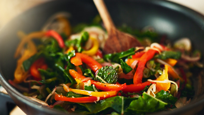 Person cooking stir-fry with vegetables