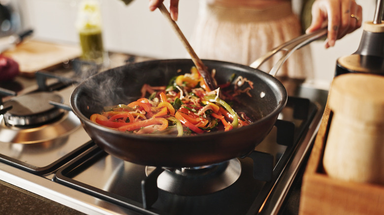Person cooking stir-fry in a pan