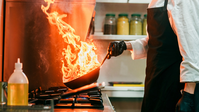 Wok cooking over a gas burner with flames