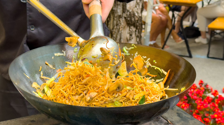 Person cooking foods in a wok