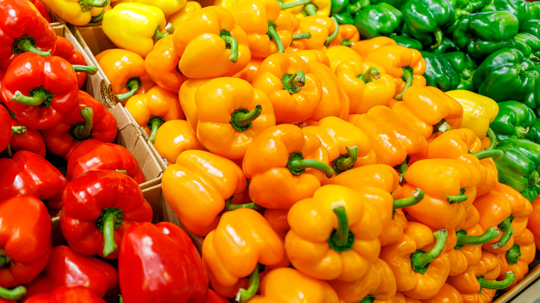 Red, yellow, and green bell peppers on display at an open air market