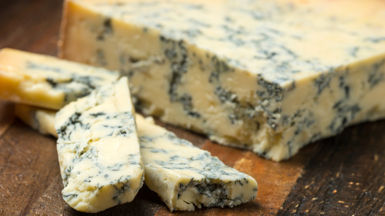 Closeup of wedges of Stilton on a wooden cutting board