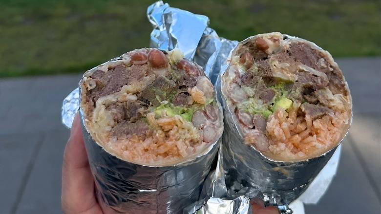A person holding two halves of a Mission burrito