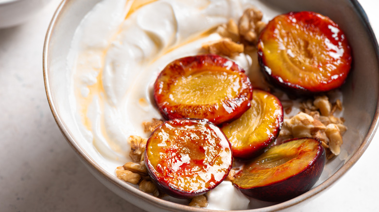 Roasted plums with yogurt, honey and nuts detailed close up
