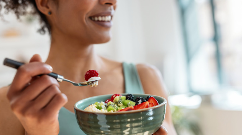 Close up of athletic woman eating a healthy fruit bowl in the kitchen at home
