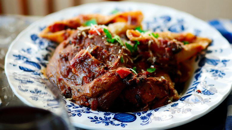 a plate of ossobuco with ragu and herbs