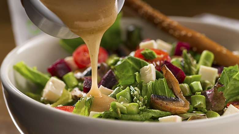 Salad being dressed with homemade vinaigrette
