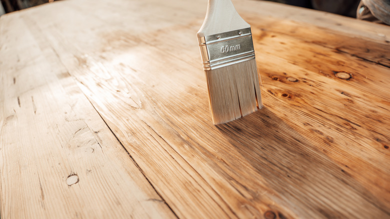 Someone oiling a wood surface with a paintbrush