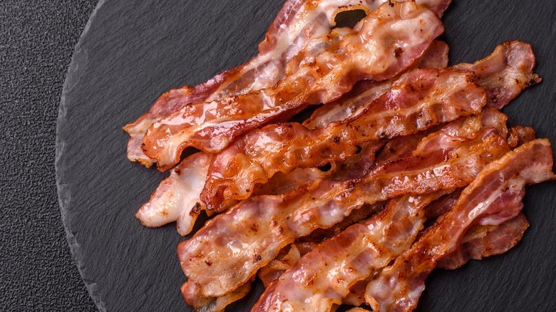 Crispy bacon strips on black background