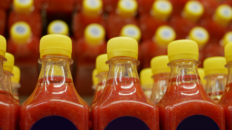 Closeup of bottles of hot sauce with others stacked on shelves behind them