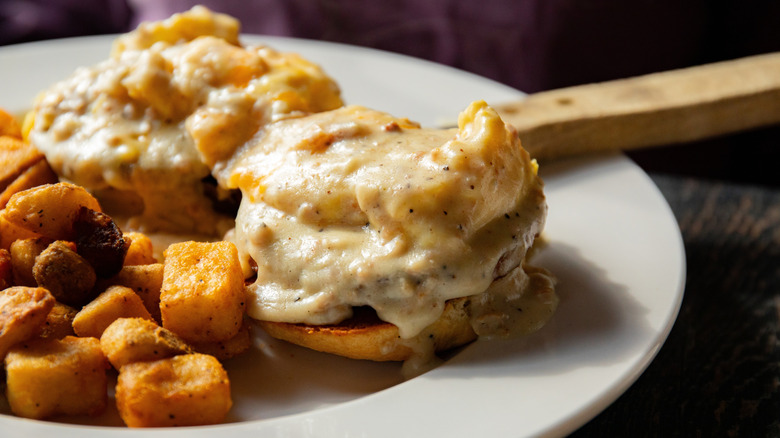 A biscuit and sausage breakfast sandwich covered in sausage gravy