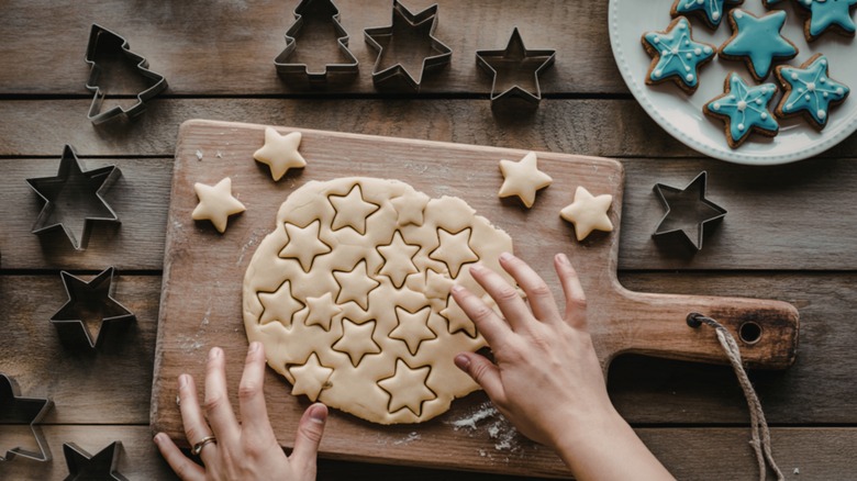 Person cutting out Christmas cookies on sheet