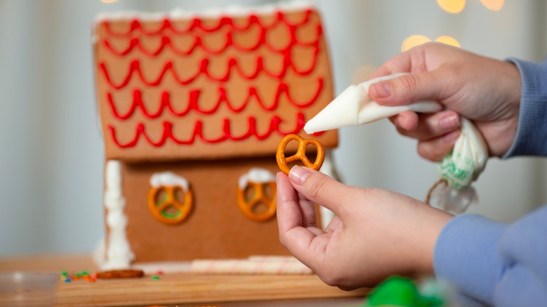 Person putting pretzels on gingerbread house