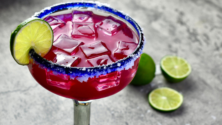 A prickly pear margarita with a lime slice garnish and salt rim