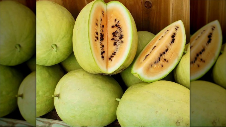 A pile of desert King watermelon with a wedge cut out of one