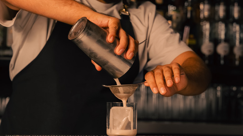 Person straining a cocktail at a bar