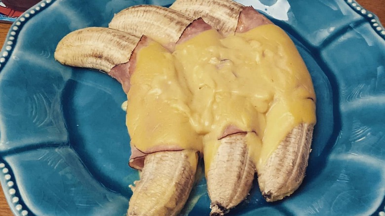 A plate of bananas wrapped in ham and topped hollandaise sauce