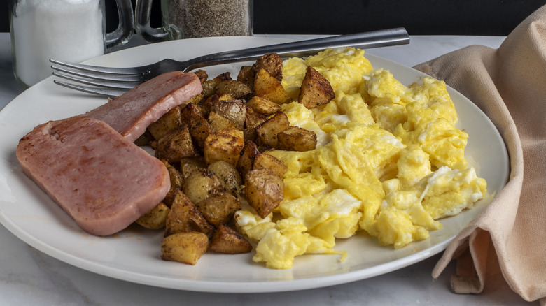 A plate of scrambled eggs with Spam and home fries