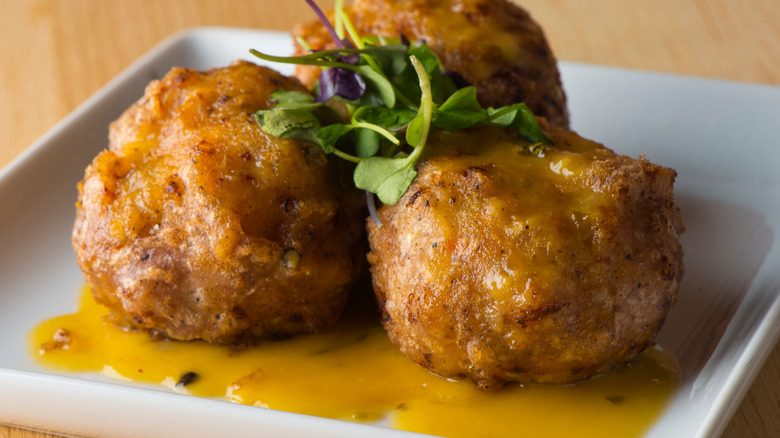 A plate of crab cakes with a spicy sauce