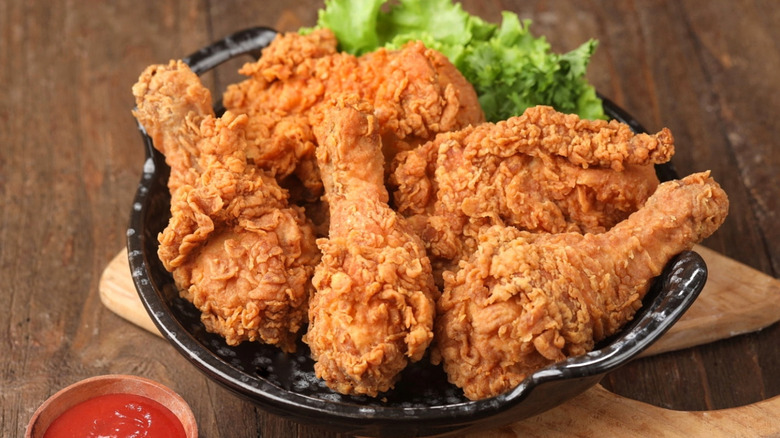 Black dish filled with fried chicken and lettuce