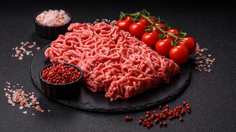 Raw ground beef with fresh tomatoes and spices ready for cooking