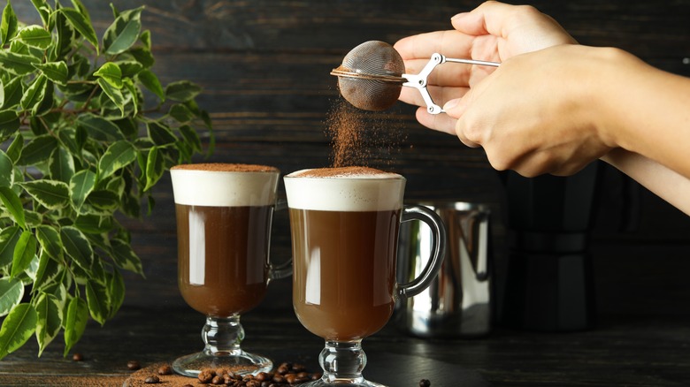 Shaking cocoa powder onto Irish coffee