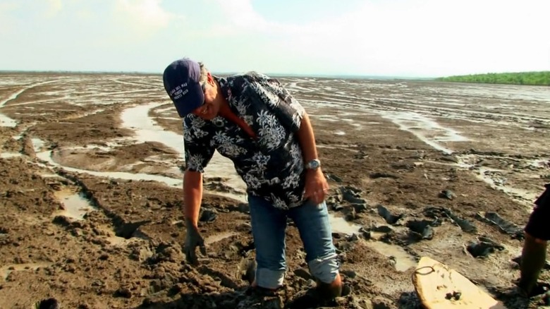 Anthony Bourdain knee-deep in mud.