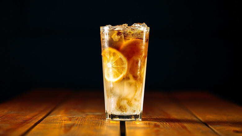 Long Island Iced Tea on wooden table black background