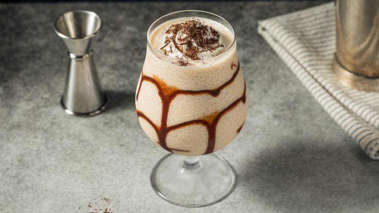 Mudslide cocktail on grey countertop with bar tools