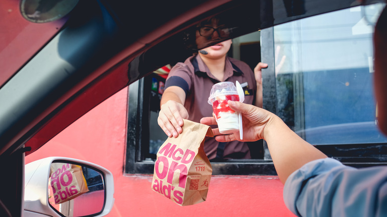 Person recieving a mcdonalds order at the drive-thru including a strawberry sundae