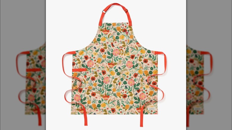 A floral apron with orange straps on a white background