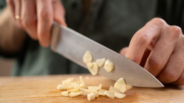 Person chopping whole garlic cloves