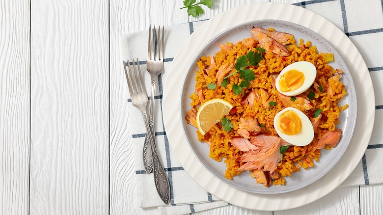 a plate of smoked salmon kedgeree on a white wooden table