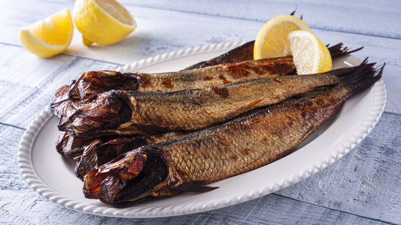 a plate of smoked kippers with lemon sits on a table