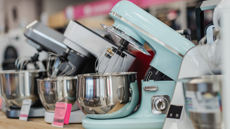 Multiple stand mixers arranged on a shelf in a retail interior