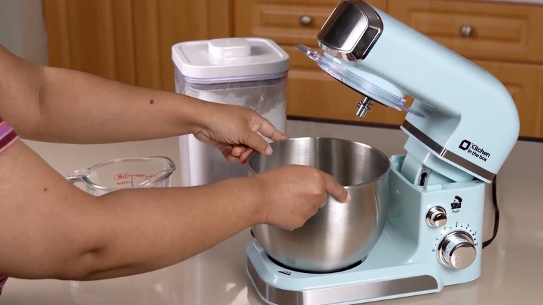 Person fitting the bowl on a light blue Kitchen in the Box stand mixer